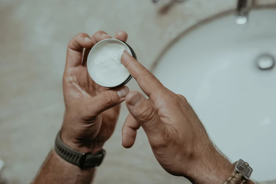 Man with small container of rich hand creams