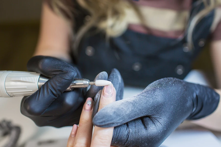 Nail professional using nail drill to remove nails