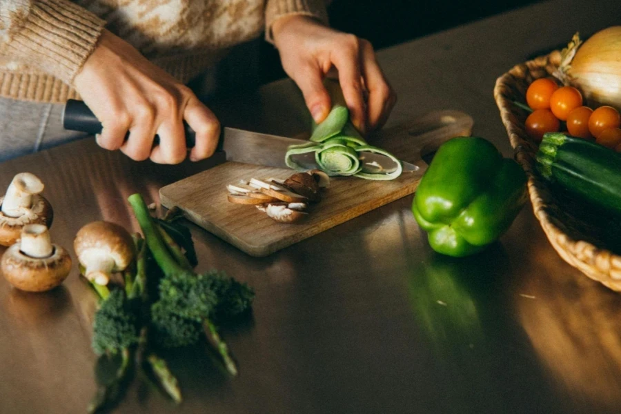 Person Slicing a Vegetable on Wooden Chopping Board