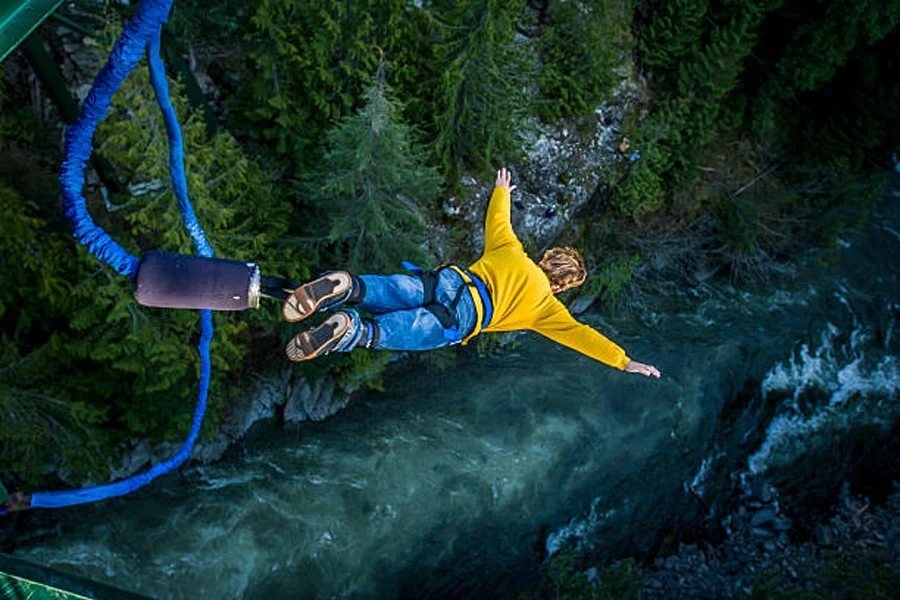 Person during bungee jump over forest and river