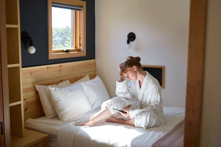 Person sitting on a bed reading on an e-reader