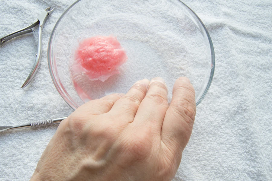 Person soaking their hand in water to remove nails