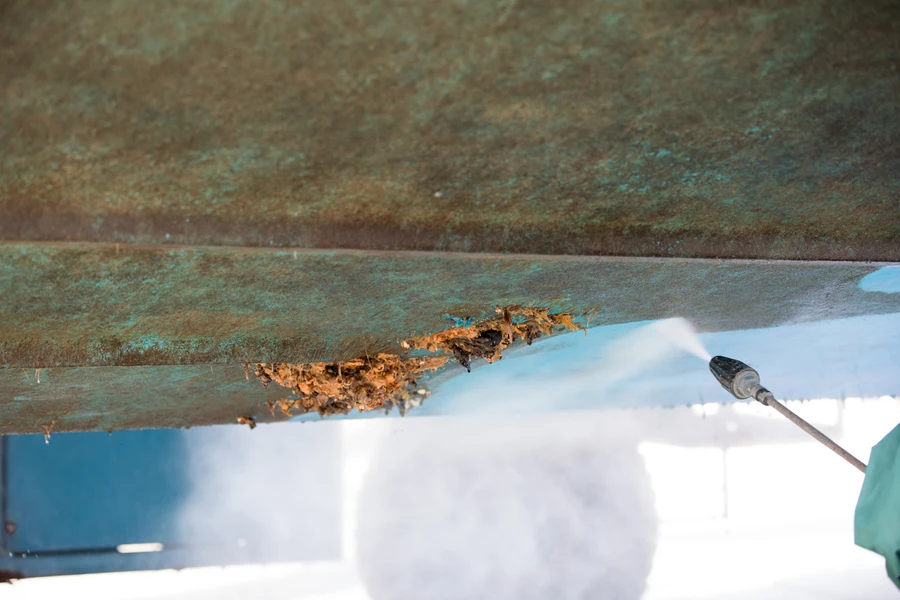 Person using a dry ice blaster on some barnacles