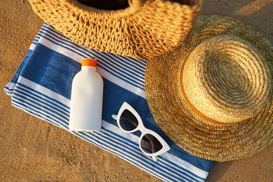 Sunscreen bottle on striped towel at the beach