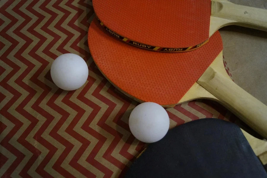 Table tennis paddles and balls arranged on a zigzag patterned surface