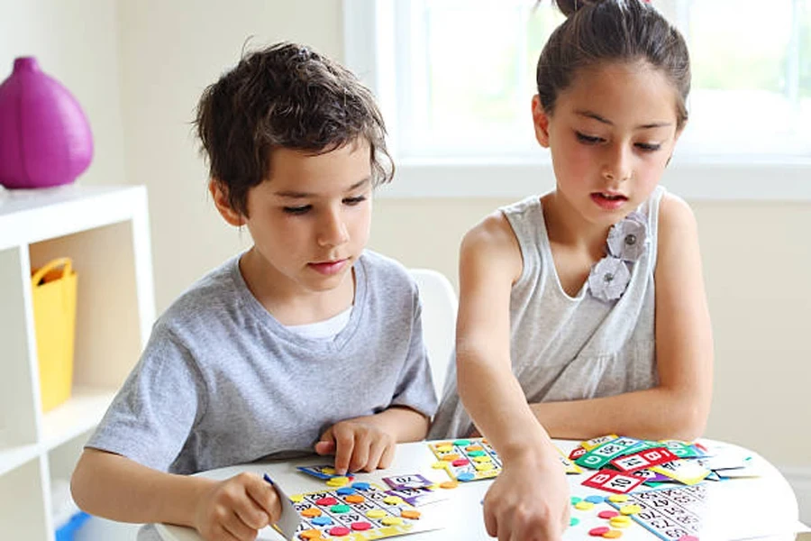 Two young children playing picture bingo indoors