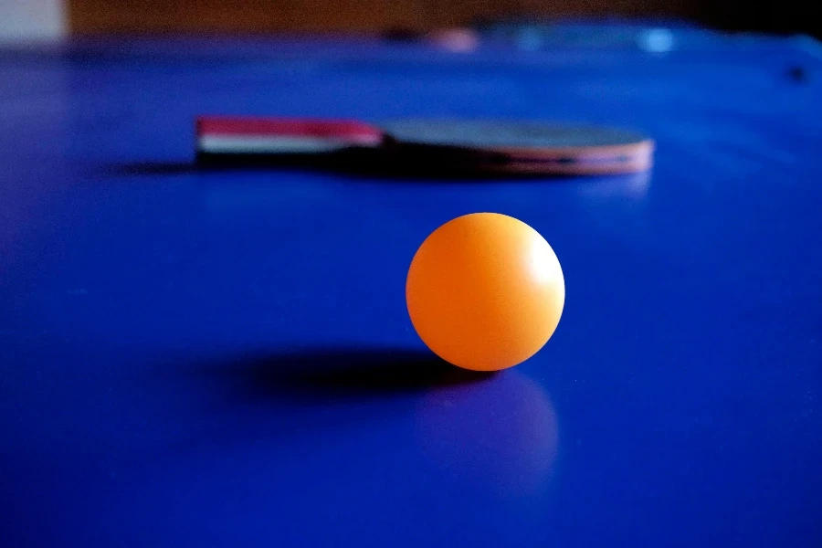 Pallina da ping pong arancione brillante con racchetta da ping pong