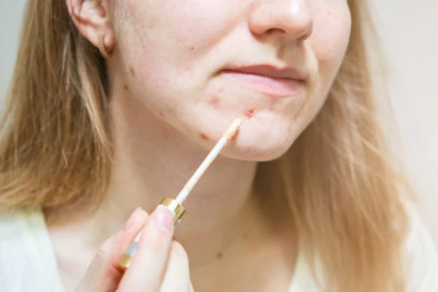 Woman applying concealer using stick to acne skin