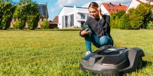 Woman controlling a robot lawn mower
