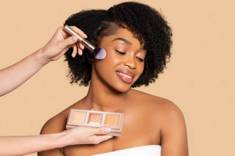 Woman having makeup applied to cheeks using pallet