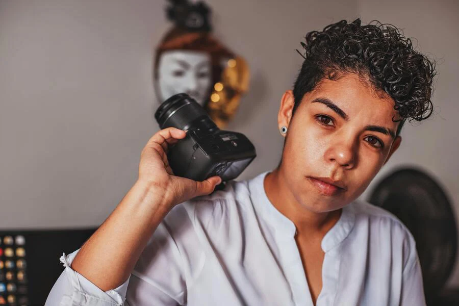 Woman in black curly hair holding a camera