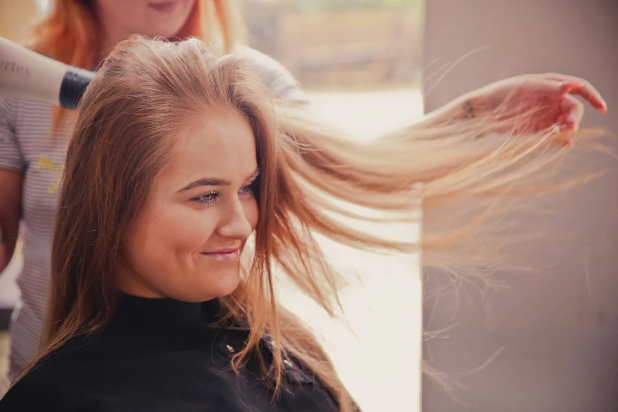 Woman in salon having hair blown dry