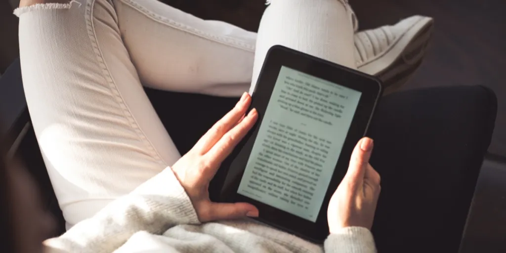 Woman sitting by the window with an e-book