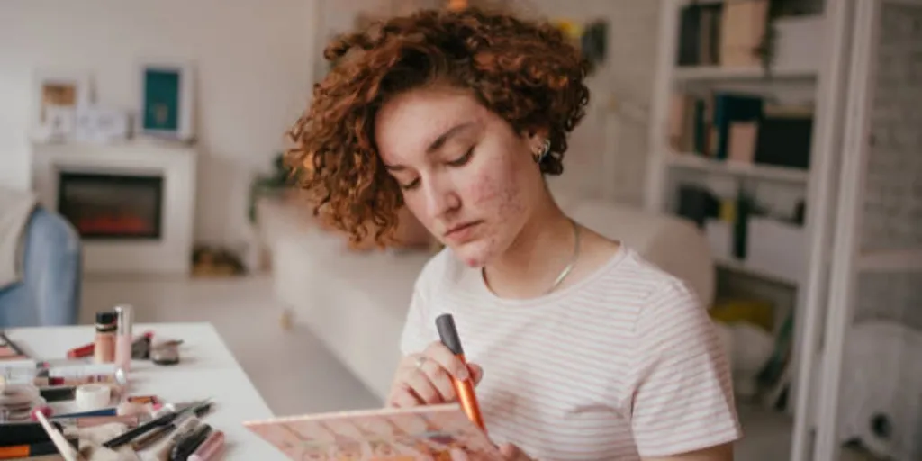 Woman with ginger hair applying acne makeup at home