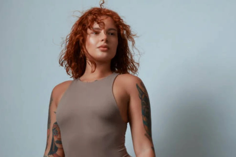 Woman with short red curly hair and tattoos on arms