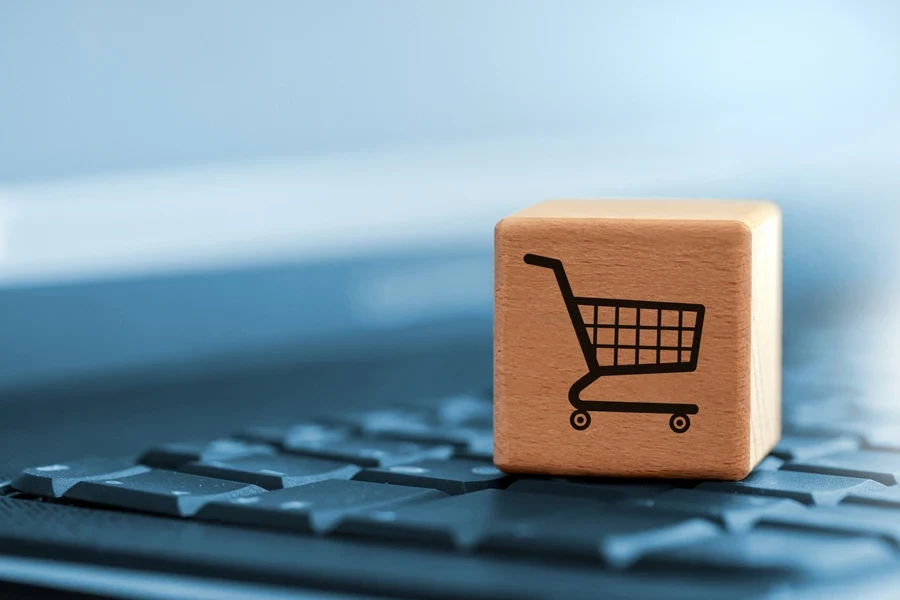 Wooden cube with a shopping trolley symbol on a laptop