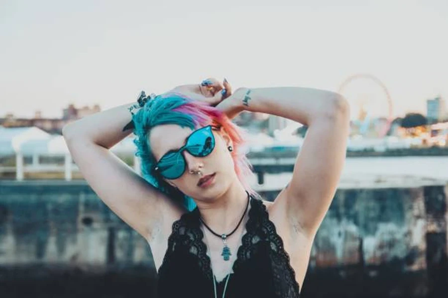 Young Female with Tattoos and Pink and Blue Hair Playing with Her Hair