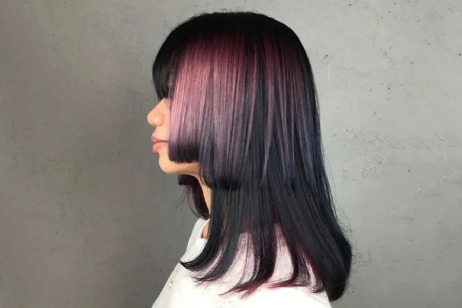 Young Japanese woman with dyed hime cut standing against wall