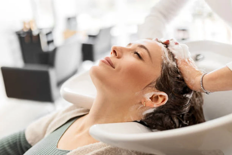 Young Woman Relaxes as Hairdresser Washes Her Hair