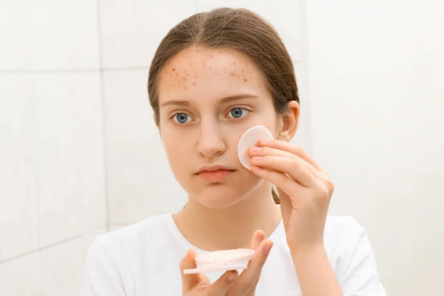 Young girl removing makeup using cotton pad in bathroom