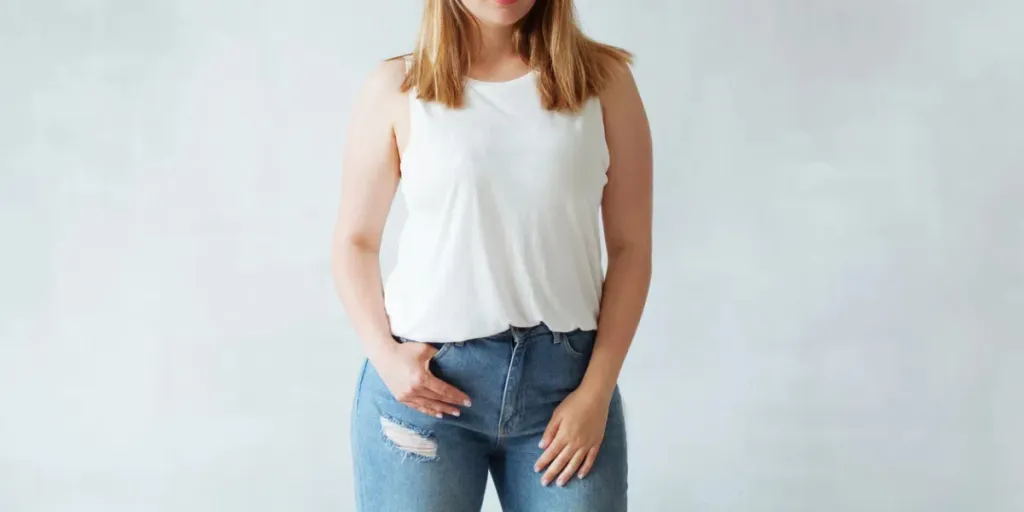 A curvy woman posing in jeans and white top