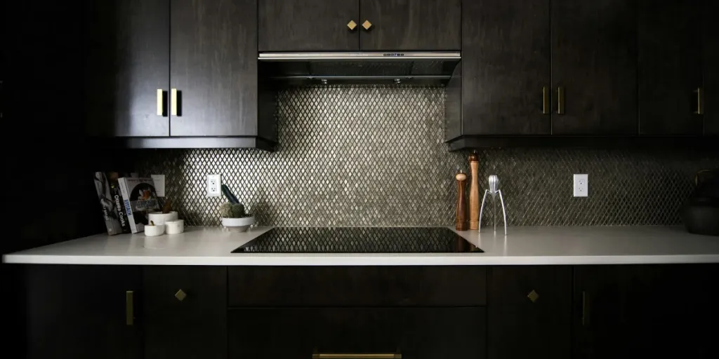 a dark kitchen with an interesting backsplash