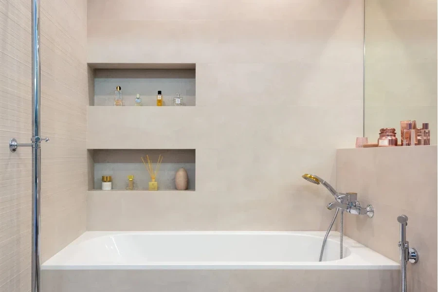 A white bathtub with silver shower head and cream niche walls