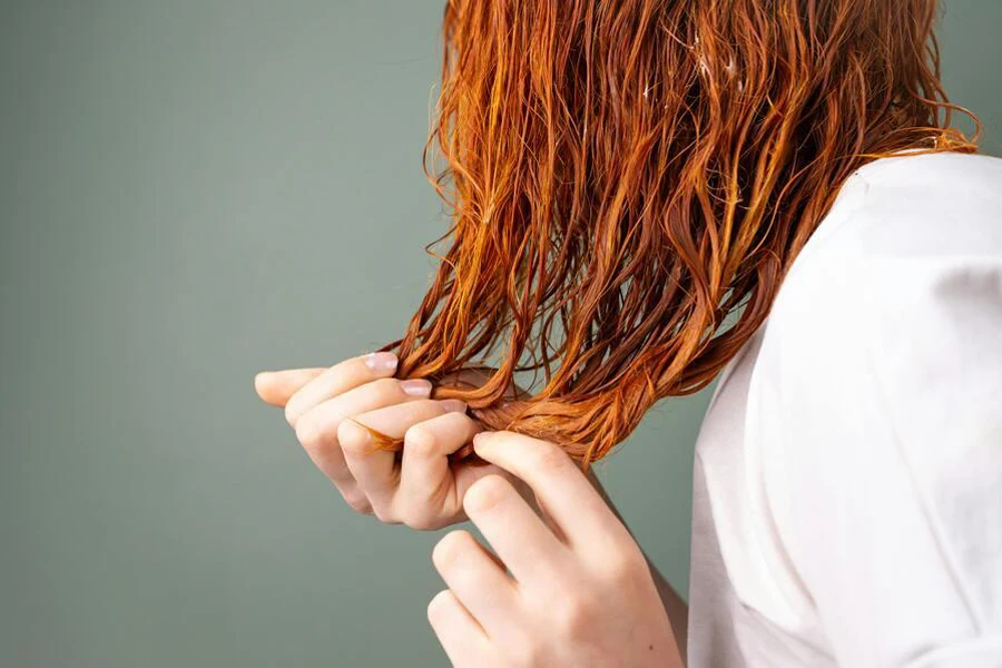 hands holding wet, wavy copper hair strands