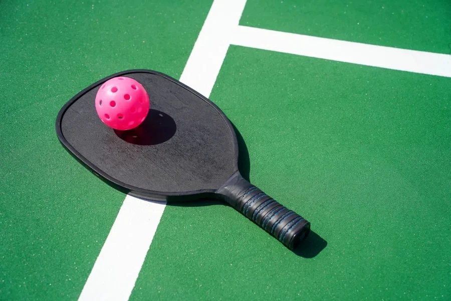 Pickleball paddle and pickle ball on court