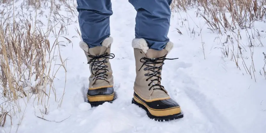 kaki pendaki atau pemburu pria dengan sepatu bot salju tebal di jalan setapak di Colorado utara di kaki Pegunungan Rocky