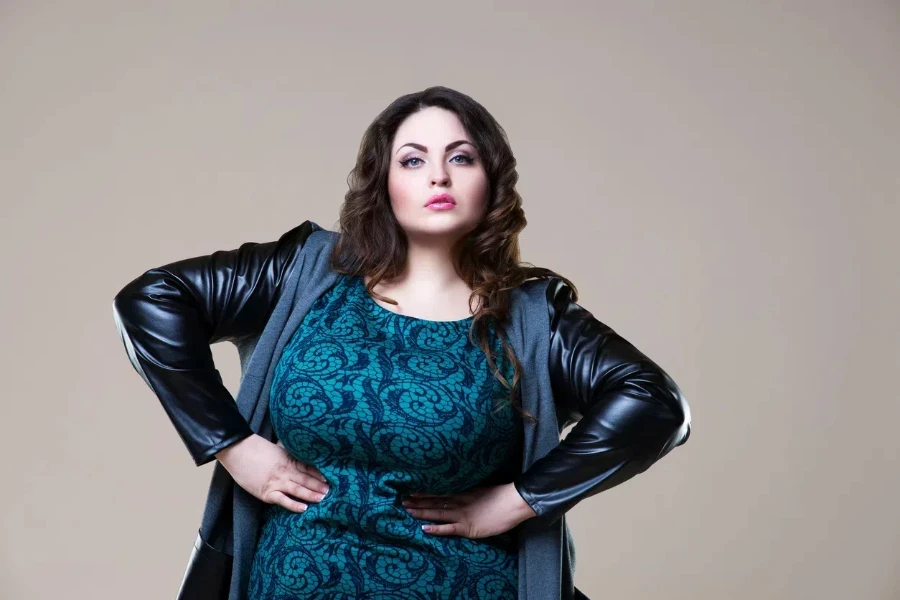 Plus-sized woman posing in a black cape coat