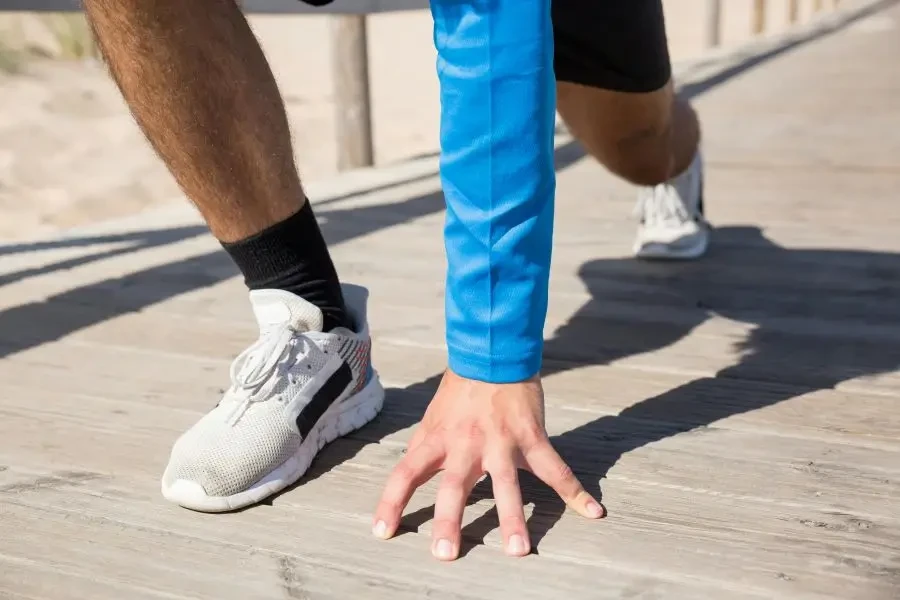 Man in athletic gear prepares for exercise on a sunny wooden deck