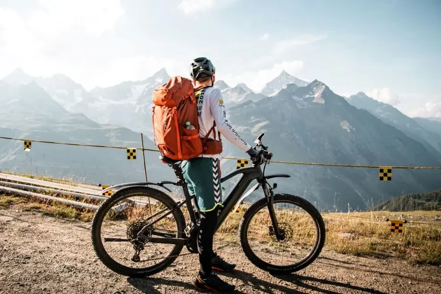 Rowerzysta z plecakiem podziwiający malowniczy widok górski w Saas-Fee w Szwajcarii