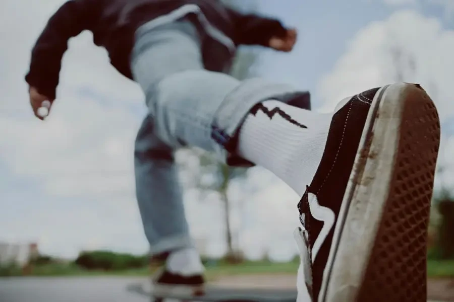 Low-angle view of a skateboarder in motion wearing sneakers and white socks on a bright day