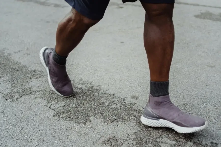 Dynamic close-up of a runners legs and athletic footwear in motion on a paved road