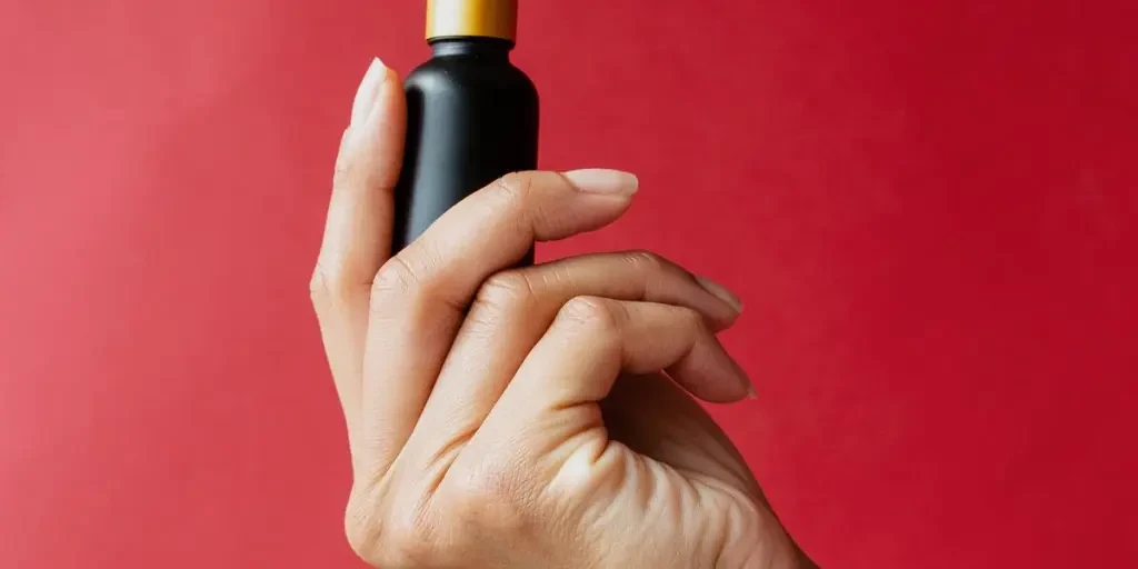 A Single Hand Holds Dropper Bottle