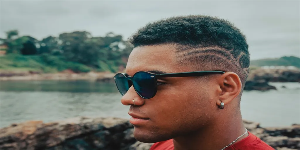 A beautiful shot of an attractive man with sunglasses with the rocks and the ocean in the background