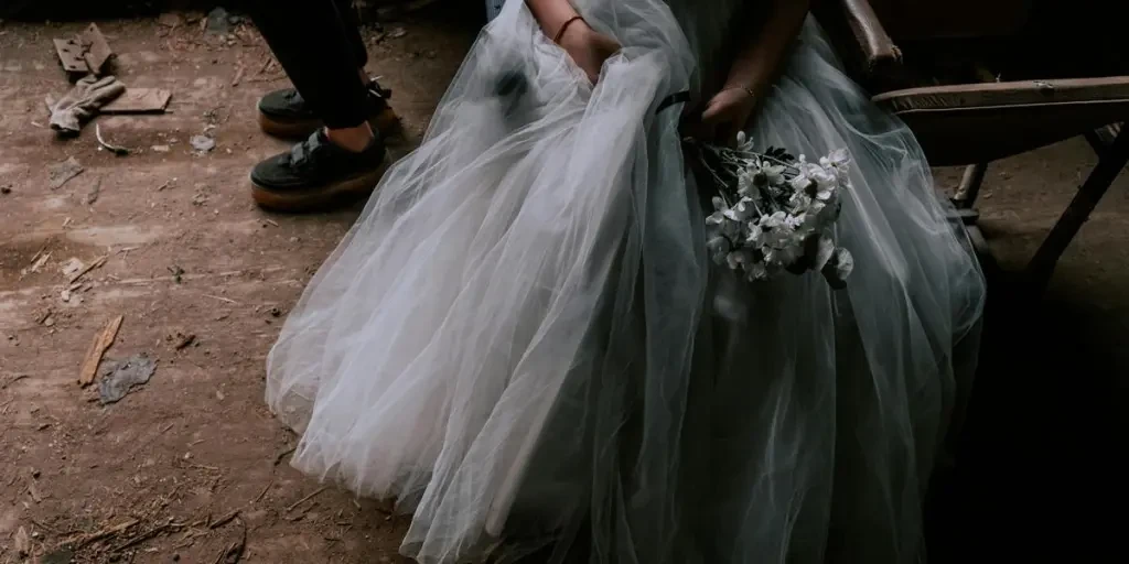 A bride in a tulle dress holding a bouquet inside a dimly lit abandoned building