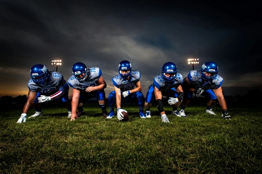 A cohesive football team lines up on the field under stadium lights, prepared for the game ahead