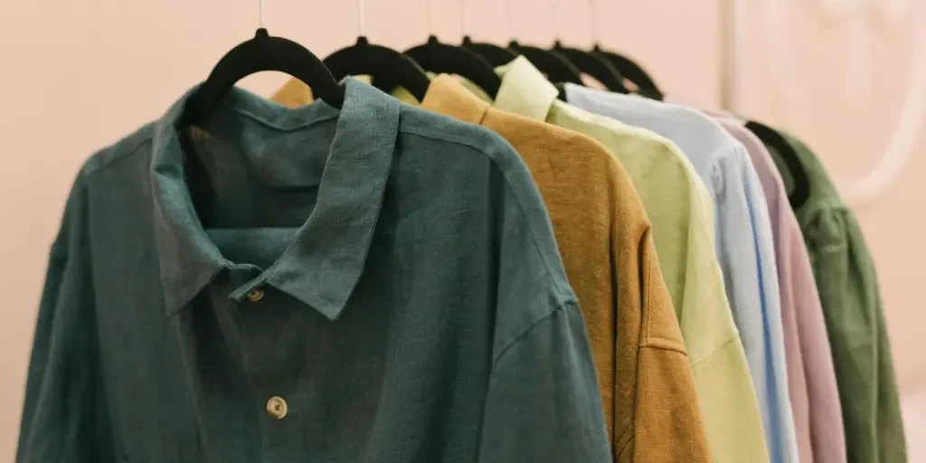 A collection of colorful shirts hanging on a rack indoors in soft lighting