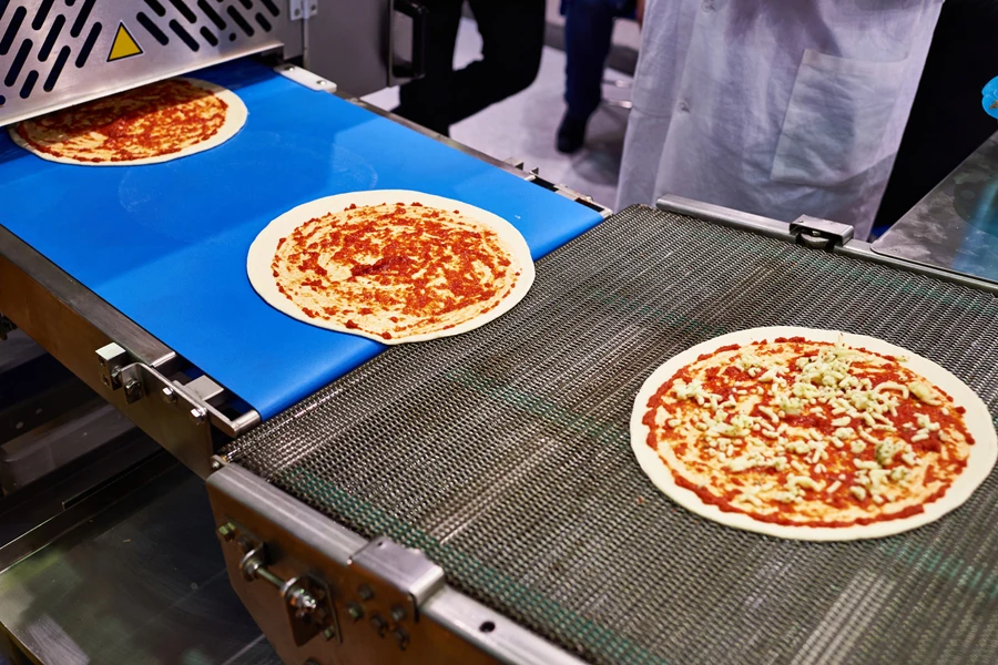 A conveyor pizza machine handling food