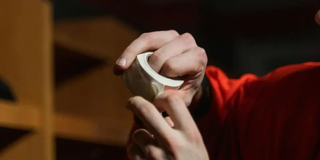 A detailed view of two hands tearing a roll of tape in a dimly lit space, creating a moody atmosphere