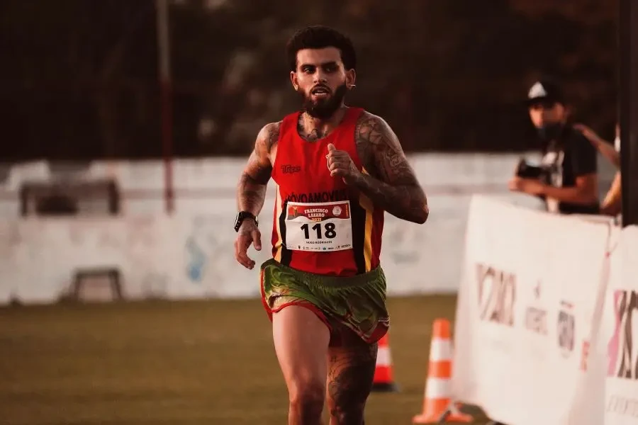 A determined male athlete competing in an outdoor marathon race on a sunny day