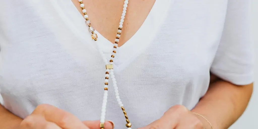 A fashionable woman wears beaded and gold necklaces with manicured nails by Photo