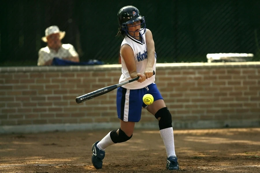 A female athlete concentrating while batting during a softball game outdoors