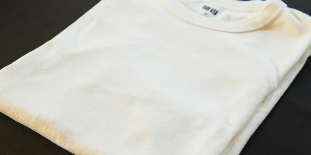 A folded white t-shirt placed on a dark surface, showcasing minimalist fashion