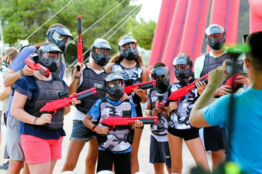 A group of people in protective gear posing for a photo during a paintball game outdoors