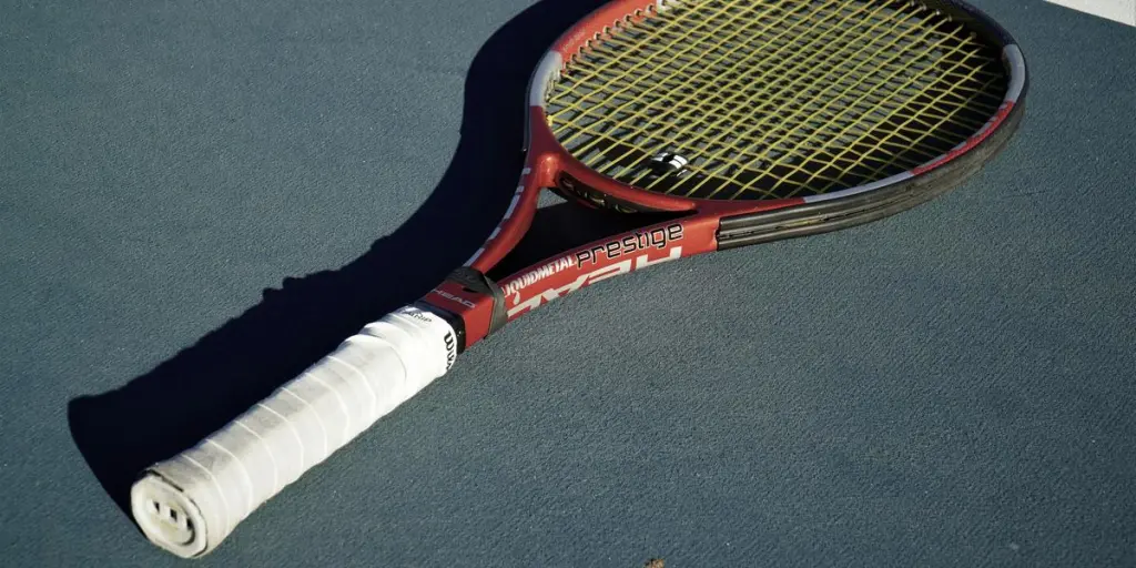 A high-quality tennis racket placed on a blue tennis court under sunlight