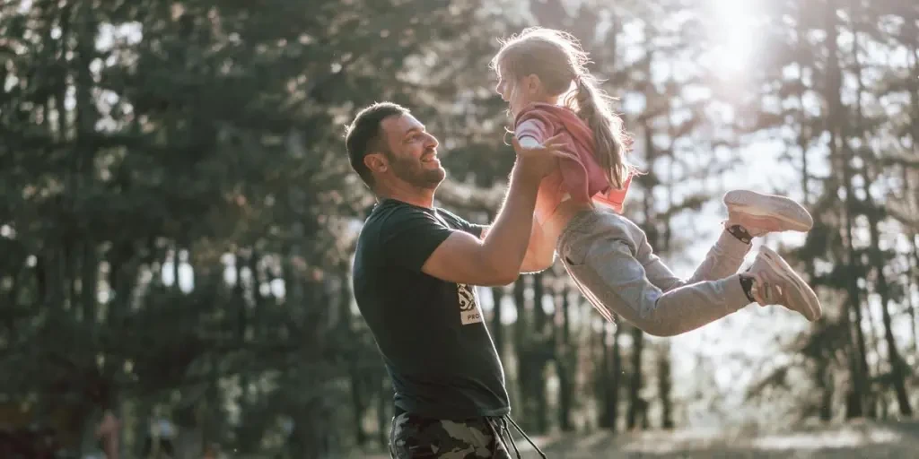 A joyful moment between a father and daughter playing in a sunny forest, capturing love and happiness