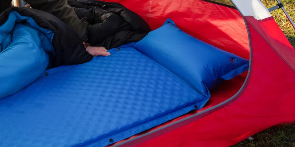 A man gets his tent and sleeping bag ready